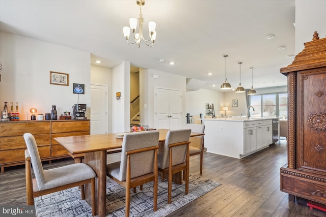 dining space with dark wood-type flooring, sink, and a notable chandelier