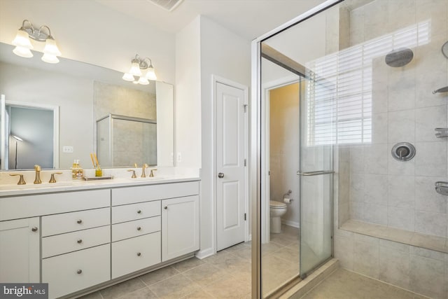 bathroom featuring tile patterned floors, toilet, a shower with door, and vanity