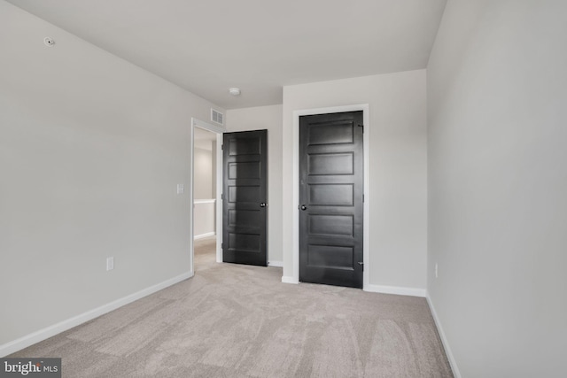 unfurnished bedroom featuring light colored carpet and a closet