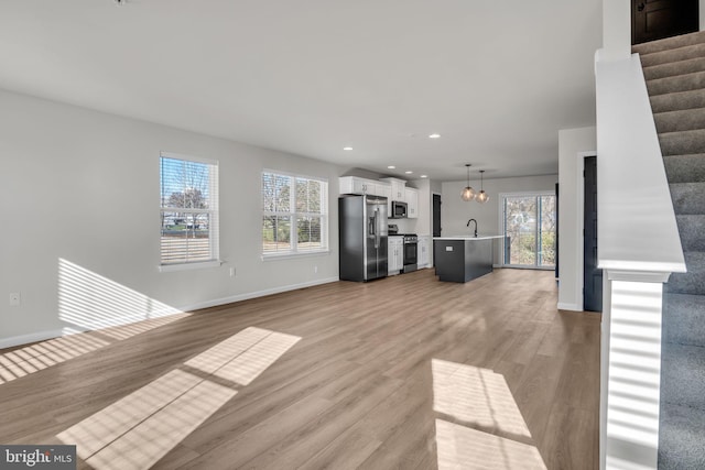 unfurnished living room featuring sink and light wood-type flooring