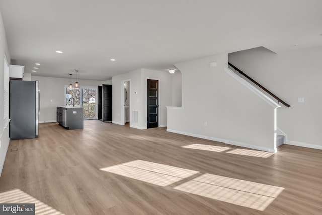 unfurnished living room featuring sink and light hardwood / wood-style floors