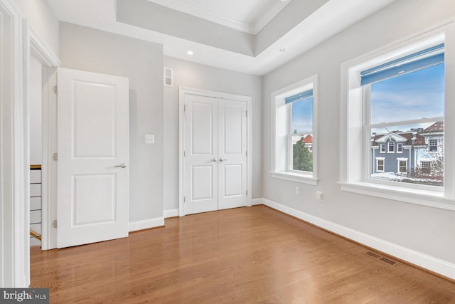 unfurnished bedroom featuring a closet, ornamental molding, and light wood-type flooring