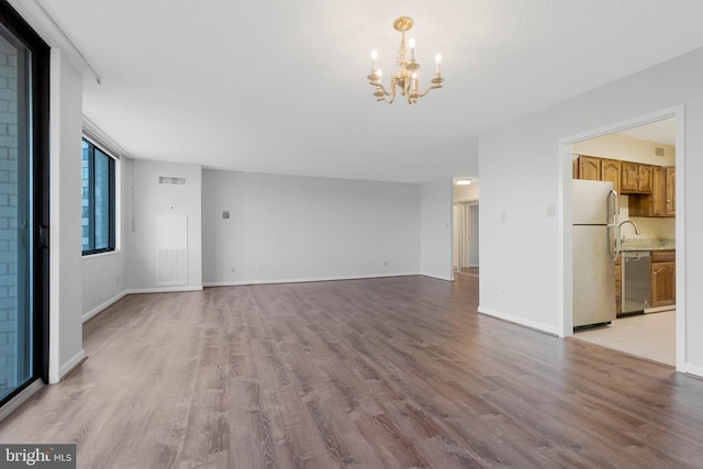 unfurnished living room featuring a chandelier and light wood-type flooring