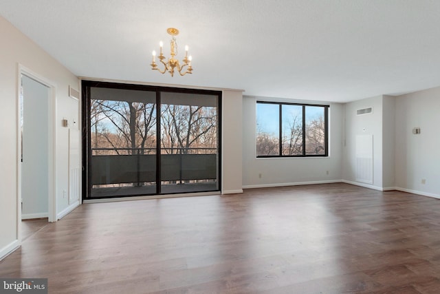 empty room with an inviting chandelier and dark hardwood / wood-style flooring