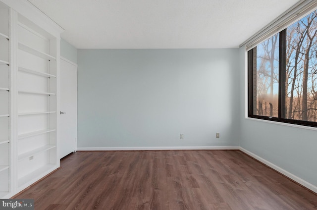 unfurnished room with dark wood-type flooring and built in features