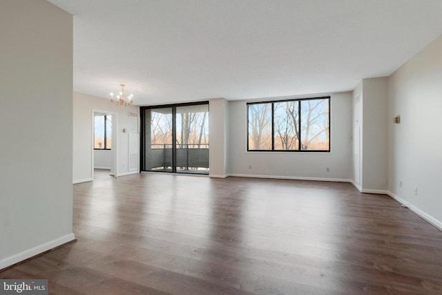 spare room with dark wood-type flooring and a notable chandelier