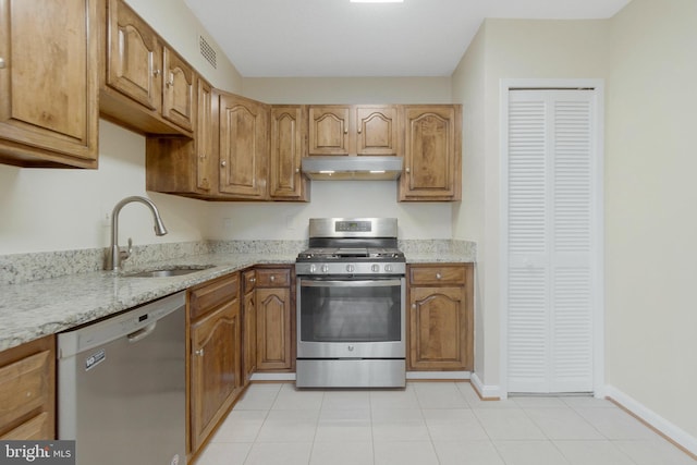 kitchen with light stone counters, appliances with stainless steel finishes, sink, and light tile patterned floors