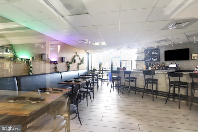 dining area with expansive windows, bar, and light hardwood / wood-style flooring