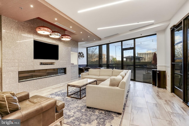 living room featuring a large fireplace and a wall of windows