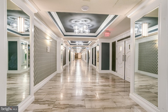 hall featuring an inviting chandelier, a tray ceiling, and crown molding