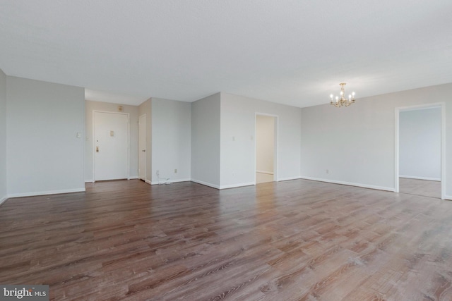 spare room featuring a chandelier and hardwood / wood-style floors