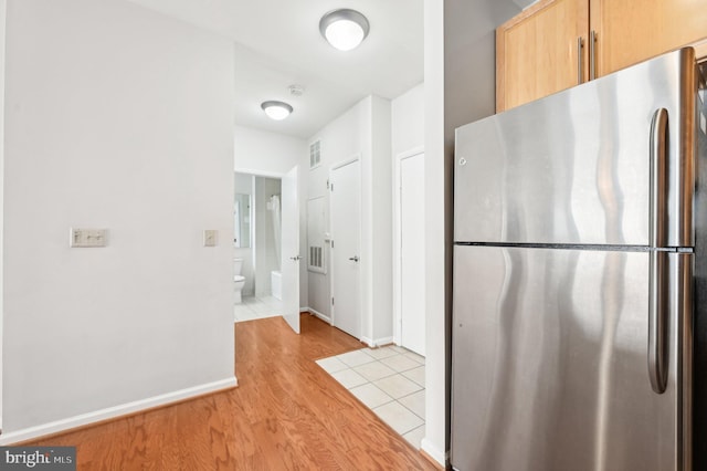 kitchen with stainless steel fridge, light brown cabinetry, and light hardwood / wood-style floors