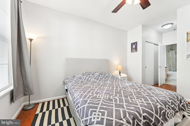 bedroom featuring ceiling fan, connected bathroom, dark hardwood / wood-style flooring, and a closet