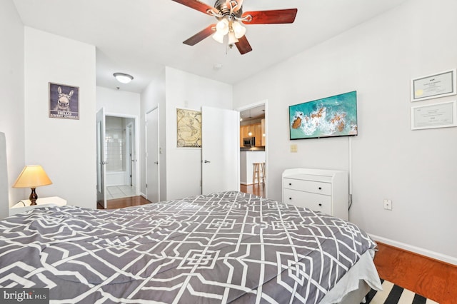 bedroom with hardwood / wood-style flooring, ensuite bathroom, and ceiling fan