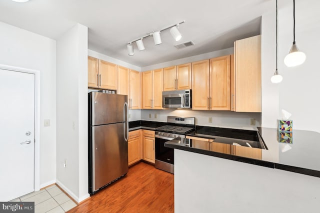 kitchen featuring pendant lighting, kitchen peninsula, stainless steel appliances, light brown cabinets, and light hardwood / wood-style flooring