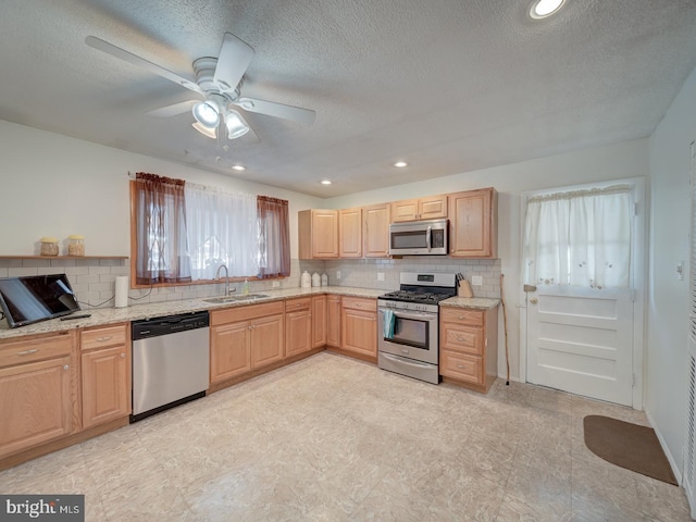 kitchen with sink, stainless steel appliances, light brown cabinetry, and tasteful backsplash