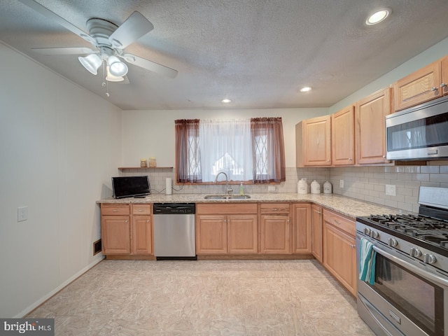 kitchen with light brown cabinetry, appliances with stainless steel finishes, sink, light stone countertops, and a textured ceiling