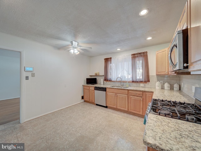 kitchen featuring ceiling fan, light stone countertops, a textured ceiling, sink, and stainless steel appliances