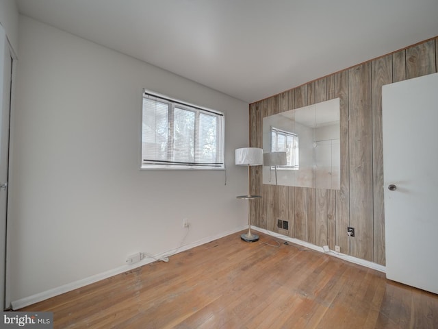 unfurnished room with wood walls and hardwood / wood-style floors