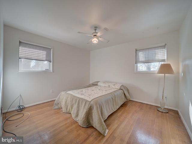 bedroom featuring ceiling fan, light hardwood / wood-style floors, and multiple windows