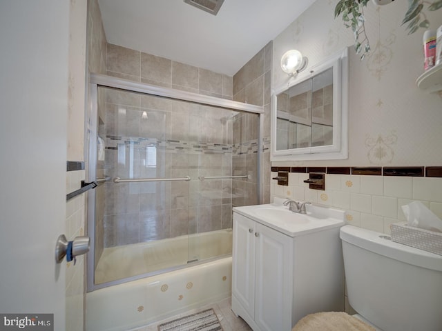 full bathroom with vanity, shower / bath combination with glass door, tile walls, and toilet