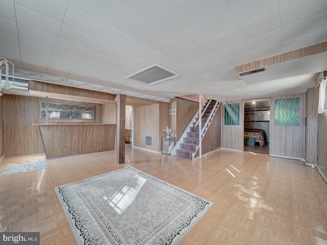 basement featuring wooden walls, a wealth of natural light, and parquet flooring