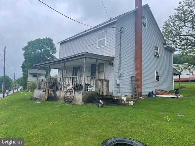 back of house featuring covered porch and a yard