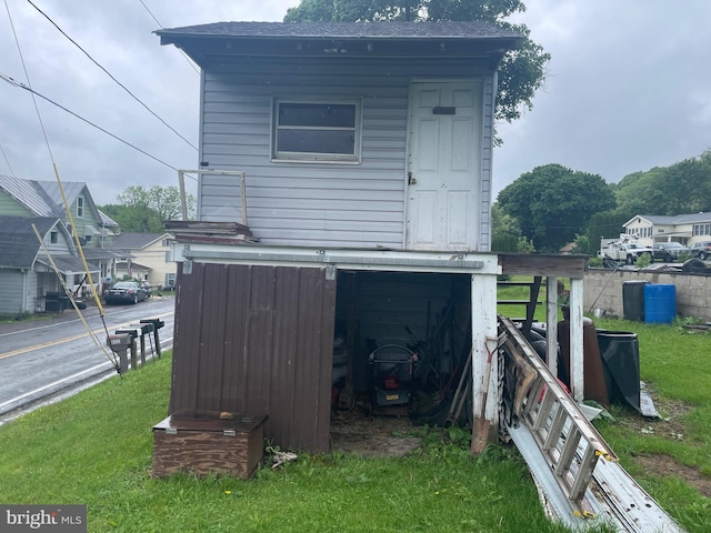 back of house with an outbuilding and a lawn