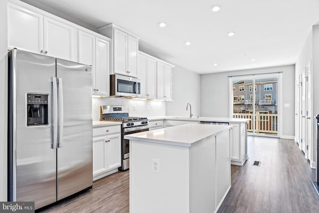 kitchen featuring sink, wood-type flooring, white cabinets, and appliances with stainless steel finishes