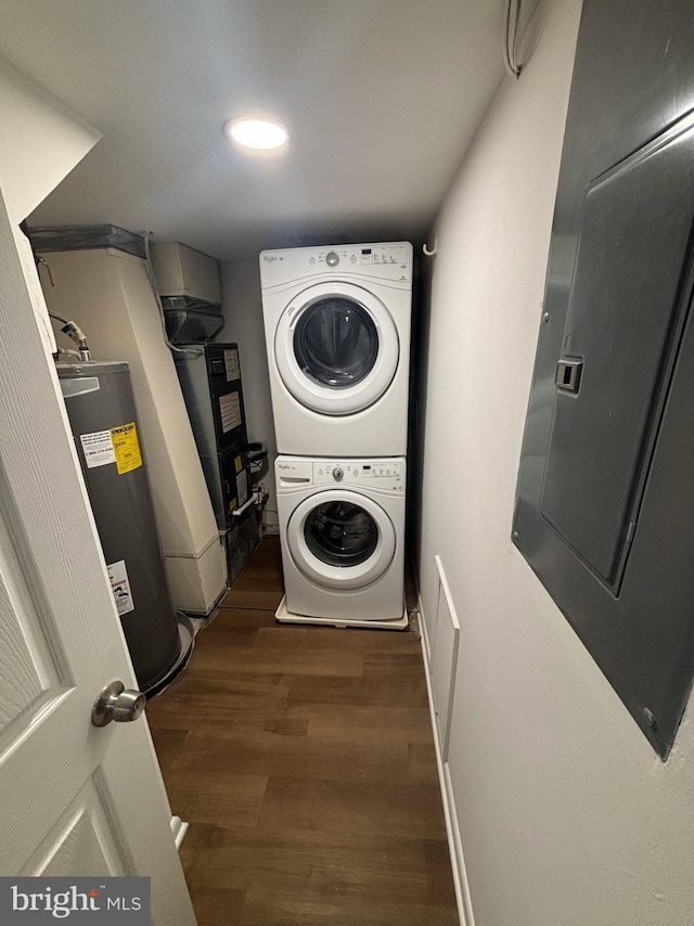 clothes washing area with heating unit, stacked washer and clothes dryer, dark hardwood / wood-style floors, and water heater