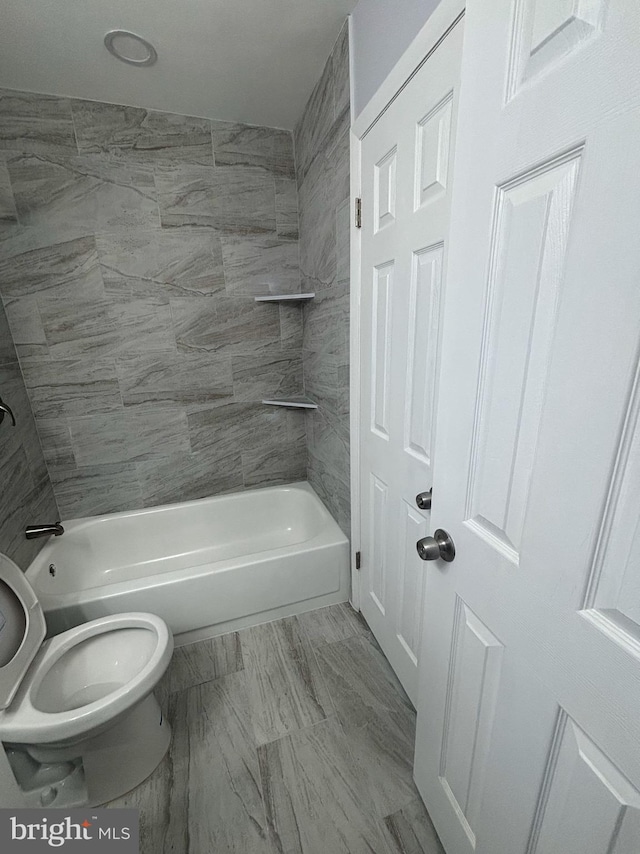 bathroom featuring toilet and tiled shower / bath combo