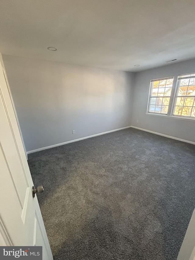 unfurnished room featuring dark carpet