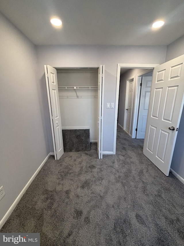 unfurnished bedroom with a closet and dark colored carpet