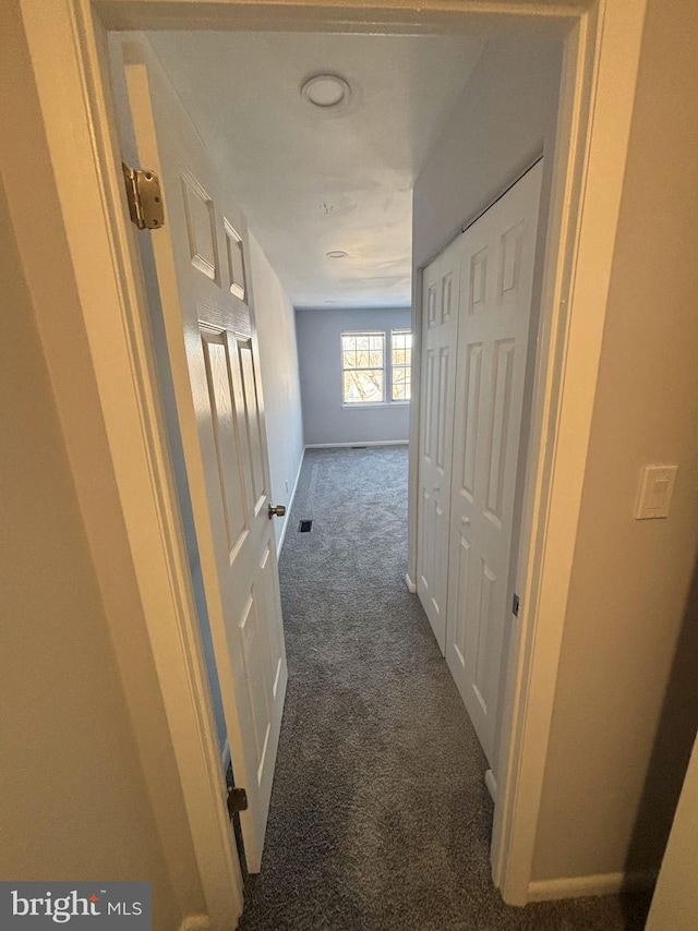 hallway featuring dark colored carpet