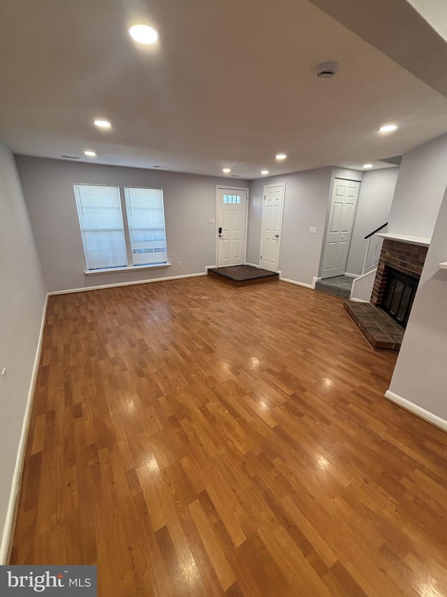 unfurnished living room with a brick fireplace and wood-type flooring