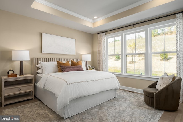 bedroom with wood-type flooring, a tray ceiling, and crown molding