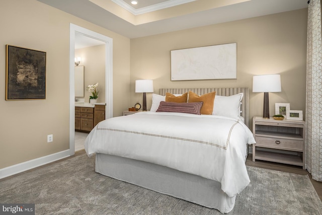 bedroom with crown molding, a tray ceiling, and ensuite bath