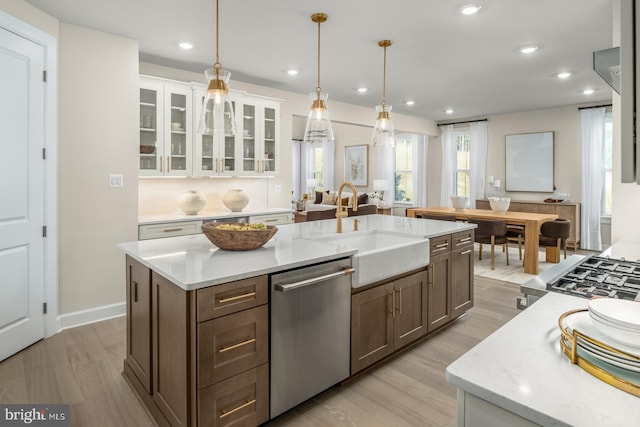 kitchen with decorative light fixtures, a center island with sink, white cabinets, and dishwasher