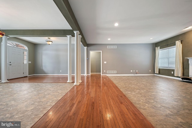 unfurnished living room featuring wood-type flooring and ornate columns