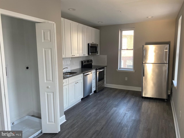 kitchen with sink, white cabinetry, dark stone counters, and appliances with stainless steel finishes