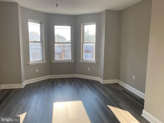 spare room with dark wood-type flooring and a healthy amount of sunlight