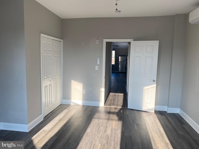 unfurnished room featuring dark hardwood / wood-style flooring and a wall unit AC