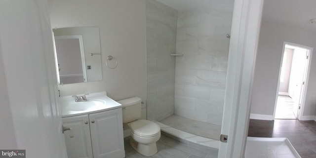 bathroom featuring vanity, toilet, and tiled shower