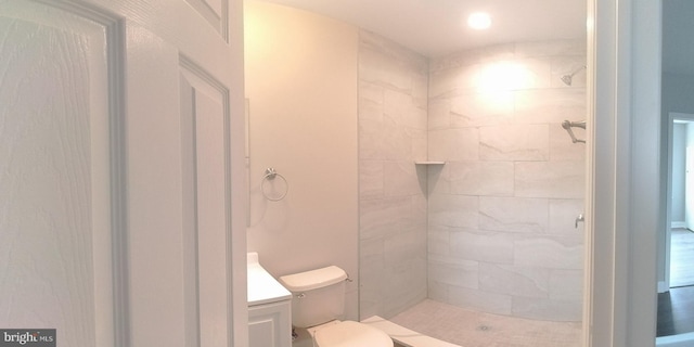 bathroom with vanity, toilet, and tiled shower