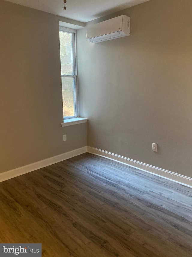 empty room with an AC wall unit and dark hardwood / wood-style flooring