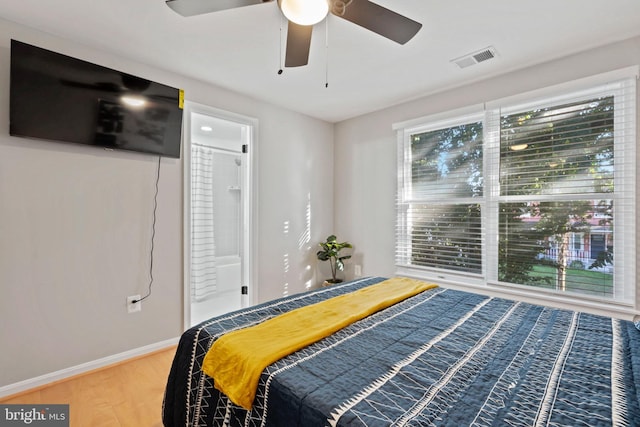 bedroom featuring ceiling fan, ensuite bath, and hardwood / wood-style floors