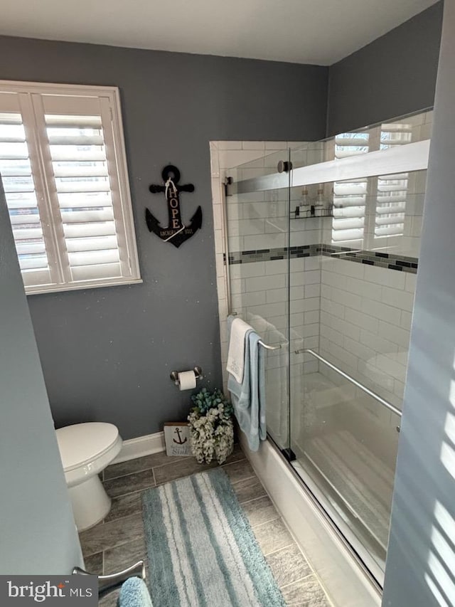 bathroom featuring shower / bath combination with glass door and toilet