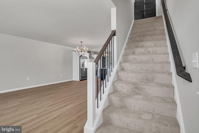 stairway featuring a notable chandelier and hardwood / wood-style flooring