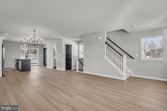 unfurnished living room with an inviting chandelier, sink, and light wood-type flooring