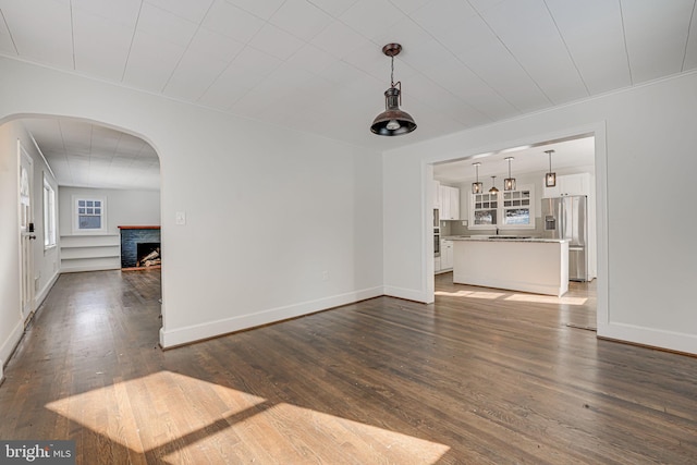 unfurnished living room with a brick fireplace and dark hardwood / wood-style floors